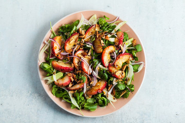 summer, very tasty salad with peaches, sweet onions and arugula with almonds on a table in a plate. simple healthy recipe