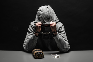 The drug addict was arrested for drug use at the table. suffering from addiction on a dark black...