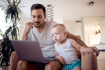 Father and son using laptop at home