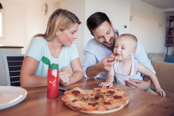 Happy family eating pizza at home