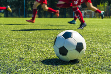 Out of focus shot of soccer balls and legs of soccer players during a soccer training session on green natural soccer pitch.