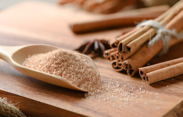 brown sugar on wood scoop and cinnamon sticks
