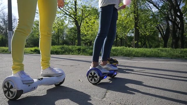 Young girls legs riding Segways gyroboards in a park slow motion