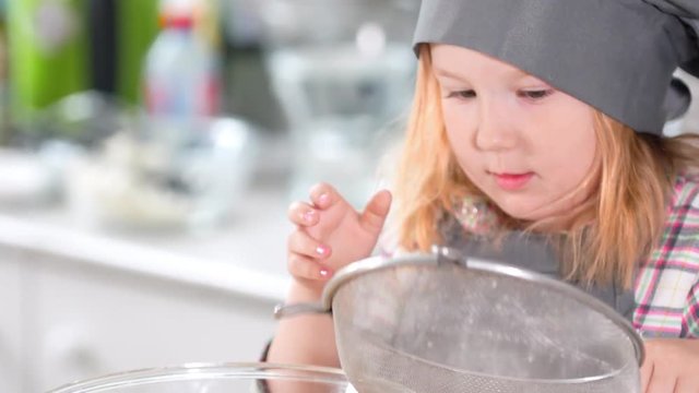 Little girl dressed as a chef playing with a sieve