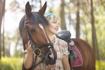 A cheerful, beautiful blonde walks in summer in sunny weather in a forest by the river with a...