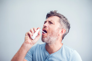 Spray for sore throat. Photo of a man who treats his throat with a spray and sprinkles it in his...