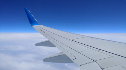 Naklejka premium Widok szarego skrzydła samolotu przez okno samolotu