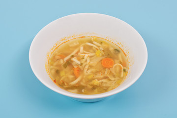 Noodle soup with vegetables on a white