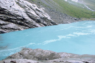 view of a crystal clear river flowing between the rocks from the melting glacier.