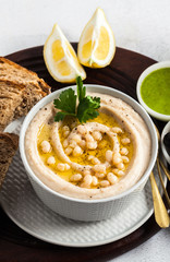 hummus of white cannellini beans, served with arugula pesto and rye bread, olives and lemon on a table