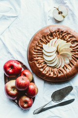 top view of fresh apples, knife and homemade apple pie on white tablecloth