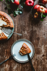 flat lay with piece of homemade apple pie, cutlery and fresh apples arranged on wooden surface