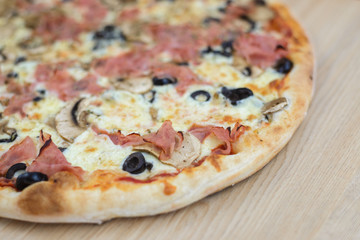 Closeup on traditional fresh pizza, top side view wooden background