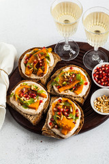 tasty bruschettes with hummus, baked pumpkin and arugula pesto on the table. vegan healthy food served with white wine
