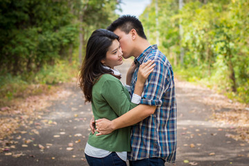Fototapeta premium Young man kiss young woman on a forest road.