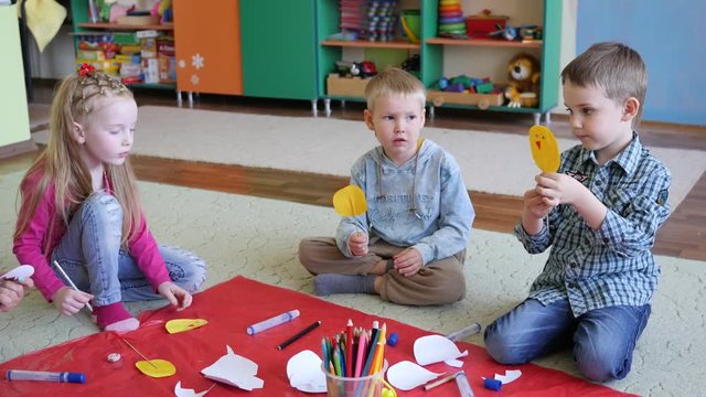Woman educator entertain kids with paper handicraft game for fine motor skills