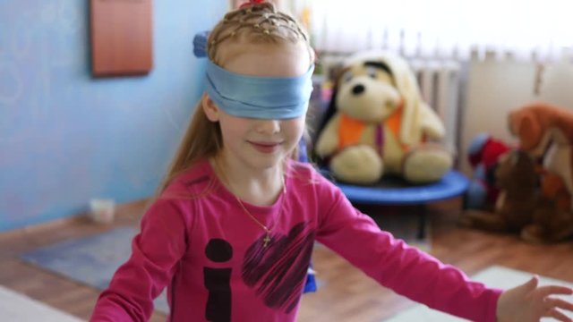 Girl chasing kids play hide-and-seek blindfolded - funny game for children in playroom