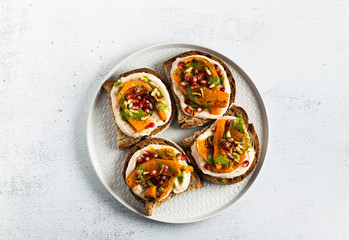 tasty bruschettes with hummus, baked pumpkin and arugula pesto on the table. vegan healthy food