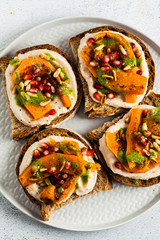 tasty bruschettes with hummus, baked pumpkin and arugula pesto on the table. vegan healthy food