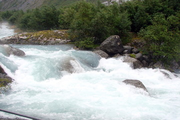 view of a crystal clear river flowing between the rocks from the melting glacier.
