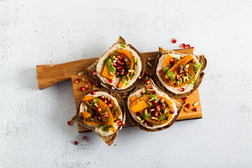 snack breads with hummus and baked pumpkin on a serving board with arugula pesto. seeds of pomegranate and pine nuts. healthy food