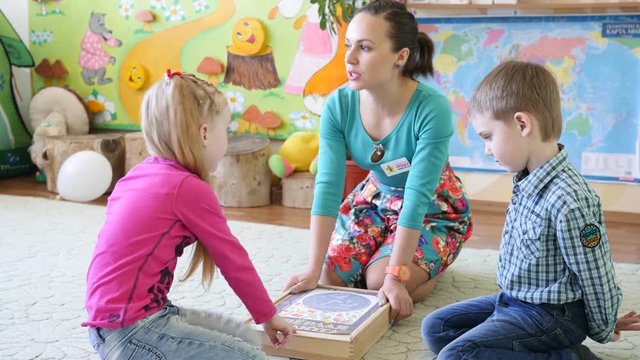 Young educator woman play with kids in educative cognitive board game in playroom