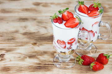 Tasty sweet dessert with yogurt and fresh strawberry on a rustic background