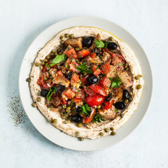 fresh Greek dakos salad on a layer of hummus. light vegan summer nutritious recipe