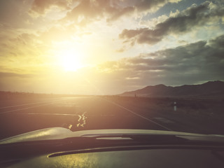 Road trip towards sunset on the white car