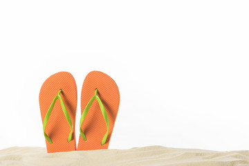 Pair of flip flops in sand isolated on white