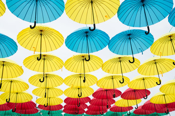 Fototapeta na wymiar Umbrella sky project installation. Umbrellas float in sky on sunny day. Outdoor art design and decor. Holiday and festival celebration. Shade and protection