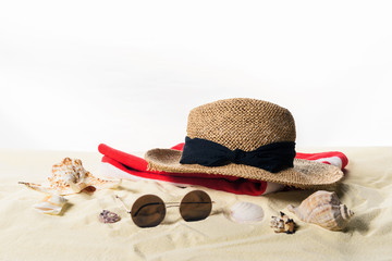 Straw hat and sunglasses with seashells in sand isolated on white