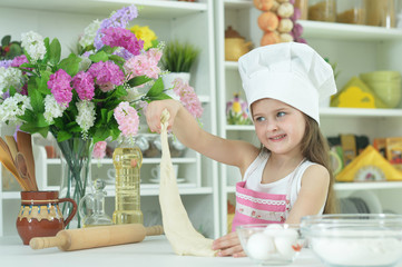 Cute girl in chefs hat making dough
