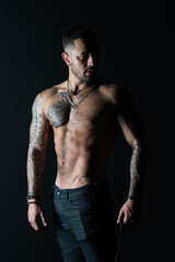 Obraz na płótnie Canvas Tattoo model with sexy belly. Man with tattooed arm and chest. Bearded man with strong torso. Sportsman or athlete in fashion jeans. Bodycare with fitness and sport