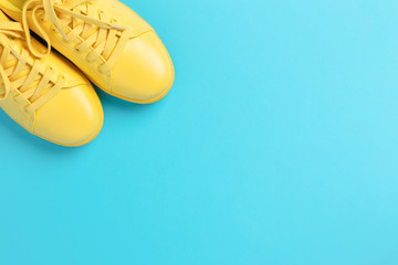 Pair of yellow shoes on blue background. Trendy summer color. Looking like the sun in the sky.