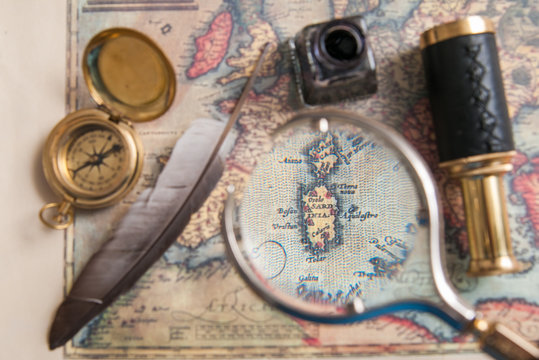 Closeup view of a magnifying glass on an old map with vintage items