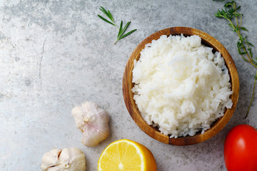 Top view image of cooked jasmin rice on metallic background with lemon, garlic and tomatoes