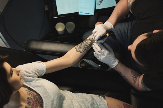 Professional tattoo artist making tattoo on hand
