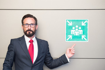Handsome professional leader pointing to meeting point sign. Man in suit and red tie warning about place for meeting. Meeting point for young businessmen and entrepreneurs. You can meet here!