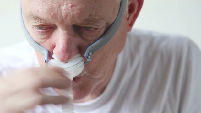 Senior with sleep apnea puts on his CPAP attachment