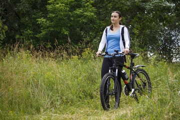 Obraz premium A young girl in the park comes with a bicycle