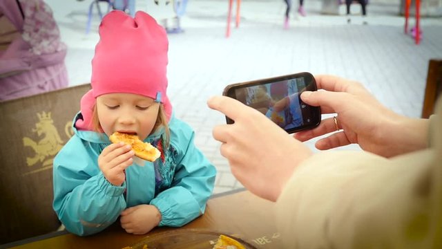 Father hands hold take picture via smartphone of his eating pizza child daughter for social media