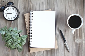 Still life, business, planning or working concept : Open notebook with blank pages, coffee cup and clock on wooden desk table, top view or flat lay with copy space ready for adding or mock up
