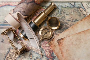 Quill pen on old paper sheets with old rolled maps and vintage items