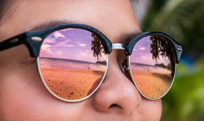 Focus on the sea view reflected through the sunglasses on the beach.