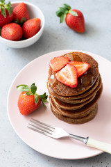 Gluten free pancakes with buckwheat and oat flour served with strawberries and honey. Top view, selective focus