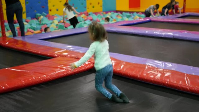Little child girl have fun jumping on trampoline playground park for kids