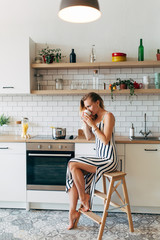 Photo of beautiful woman in long striped dress in kitchen