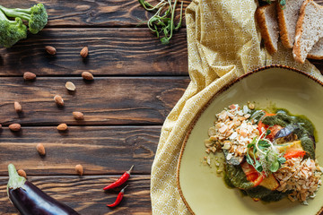 flat lay with vegetarian salad, almonds, chili peppers and pieces of bread on wooden tabletop