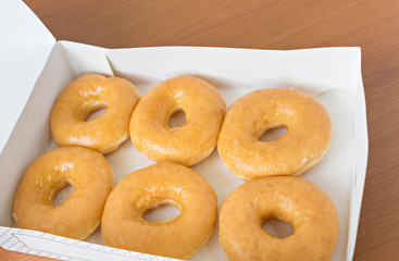 donuts in a box on wood table.